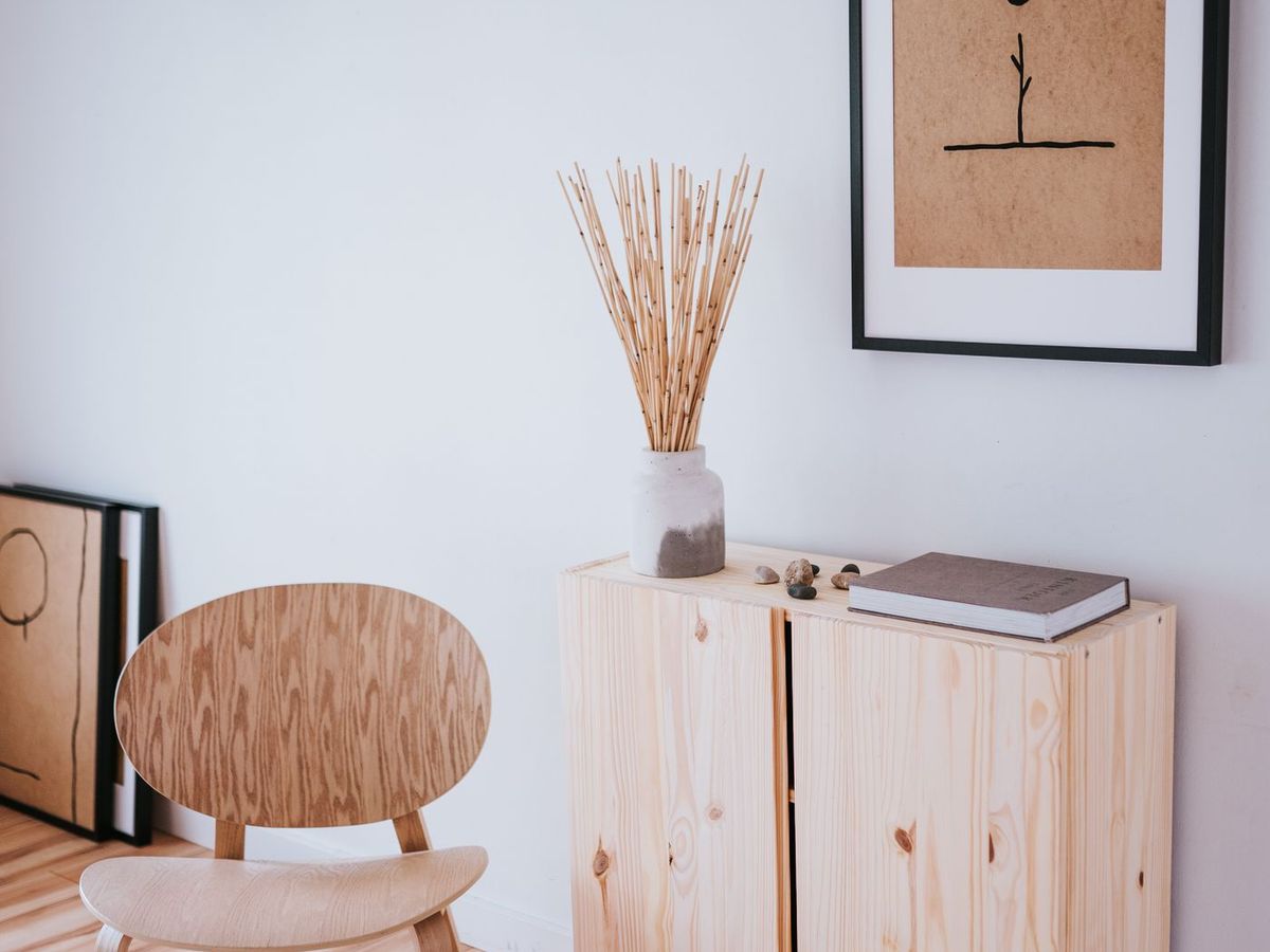 A light timber storage cabinet and chair against a plain wall