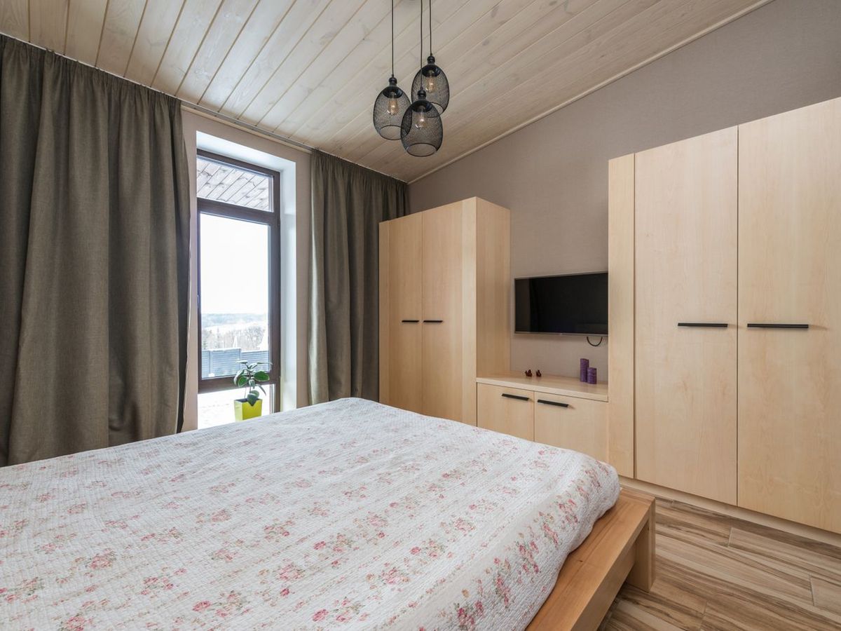 A bedroom with a light-wood fitted wardrobe run and matching TV unit