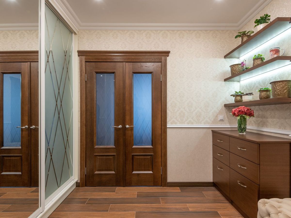 Wooden door shutters hung in a finished interior, with a fitted storage unit alongside