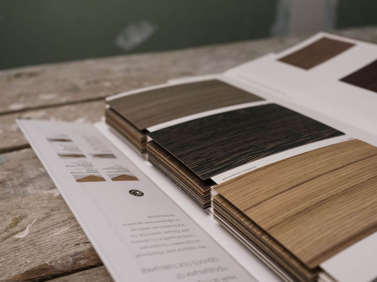 A decorative laminate sample book open on a counter, showing woodgrain and solid shades