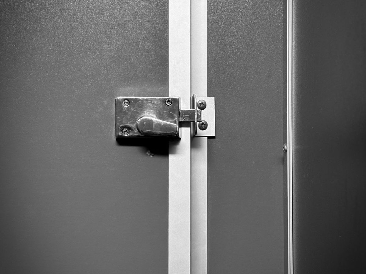 A stainless steel catch and fixing plate on a cabinet door edge