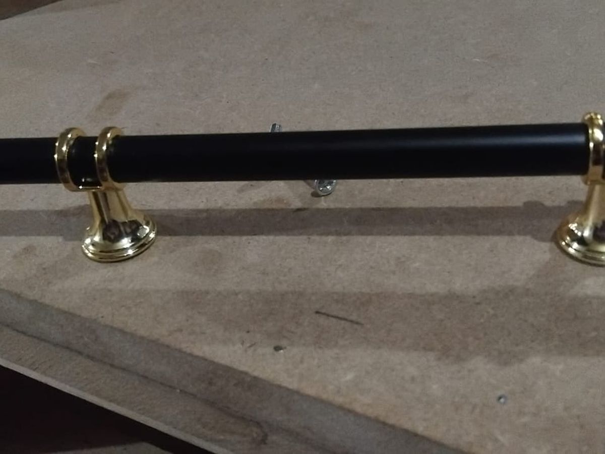 A black and brass pull handle from our hardware counter, laid on a board